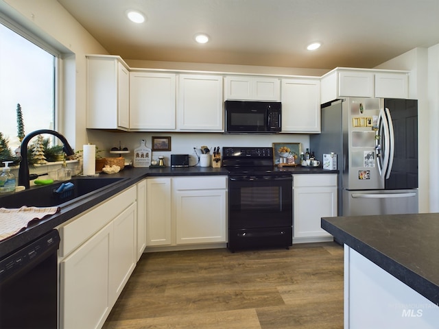 kitchen featuring sink, white cabinetry, dark wood-type flooring, and black appliances