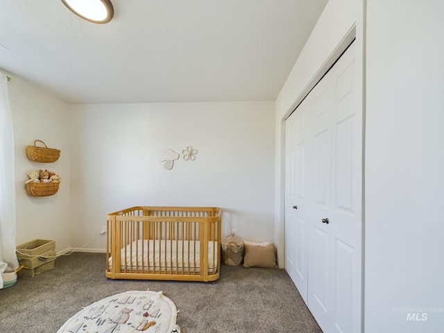 carpeted bedroom featuring a crib and a closet