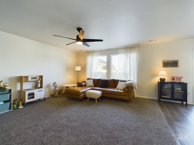 living room with ceiling fan and dark hardwood / wood-style flooring