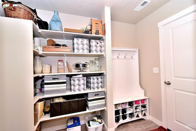 mudroom featuring a textured ceiling, baseboards, wood finished floors, and visible vents