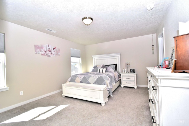 bedroom featuring visible vents, a textured ceiling, baseboards, and light colored carpet