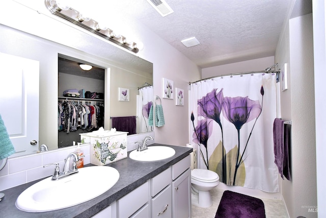 bathroom featuring double vanity, toilet, visible vents, and a sink