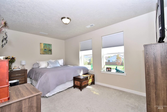 carpeted bedroom with a textured ceiling, baseboards, and visible vents