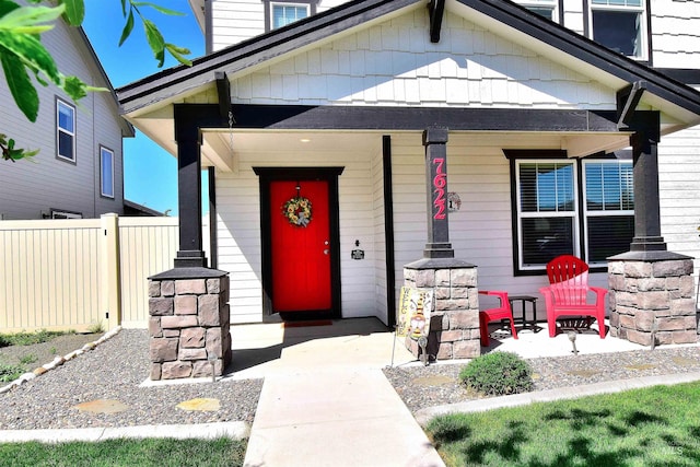 property entrance featuring fence and covered porch
