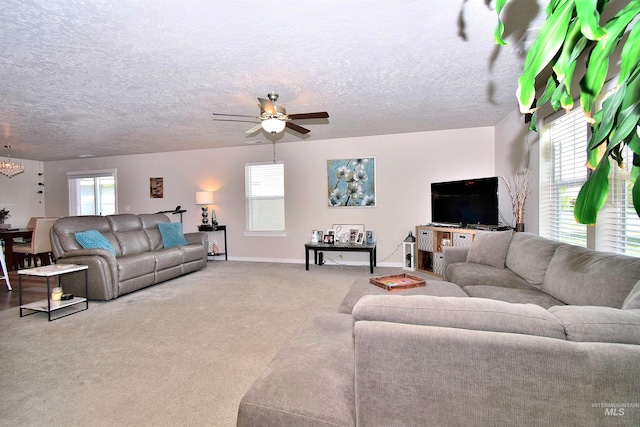 carpeted living room featuring baseboards and ceiling fan with notable chandelier