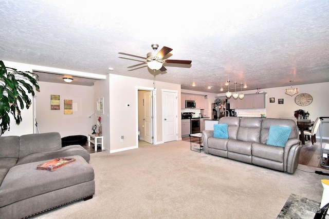 living area with baseboards, a textured ceiling, ceiling fan with notable chandelier, and light carpet