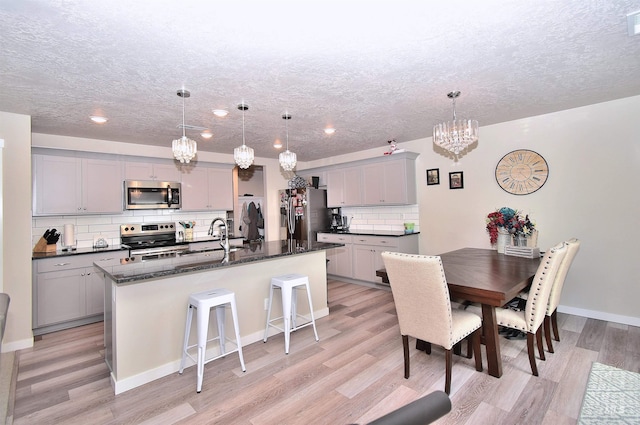 kitchen with gray cabinets, a textured ceiling, a chandelier, and stainless steel appliances