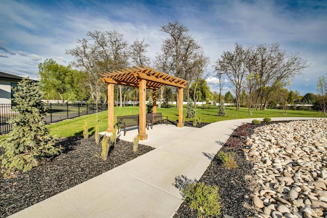 view of community featuring a patio area, fence, a lawn, and a pergola