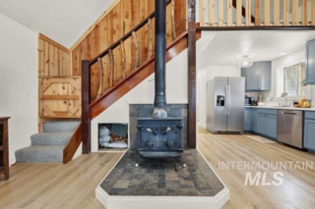 living room with sink, light wood-type flooring, and a wood stove