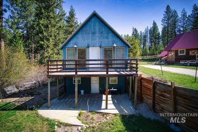 rear view of house featuring a patio area, fence, and a deck
