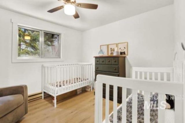 bedroom with hardwood / wood-style flooring, a crib, and ceiling fan