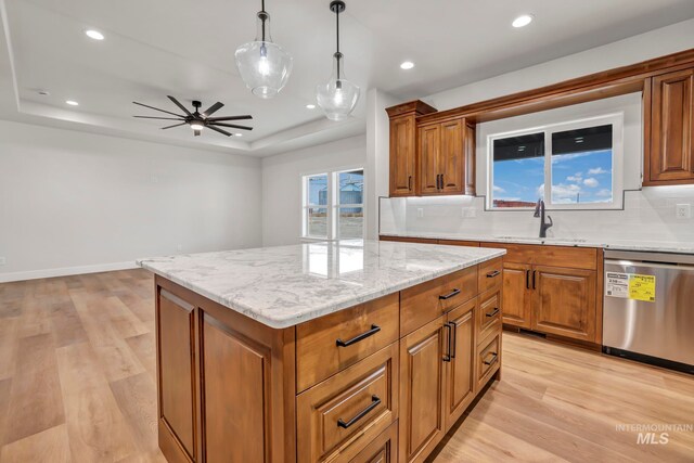 kitchen with a sink, light wood-style floors, dishwasher, brown cabinetry, and a raised ceiling