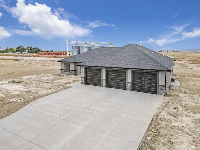 view of side of home featuring a shingled roof, stone siding, concrete driveway, and stucco siding