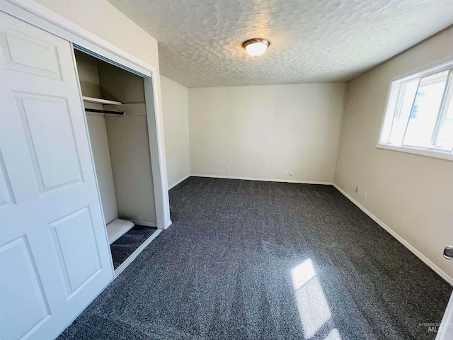 unfurnished bedroom featuring a closet, dark colored carpet, and a textured ceiling