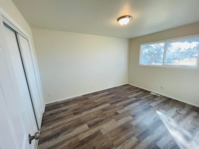 unfurnished bedroom with a closet and dark hardwood / wood-style floors