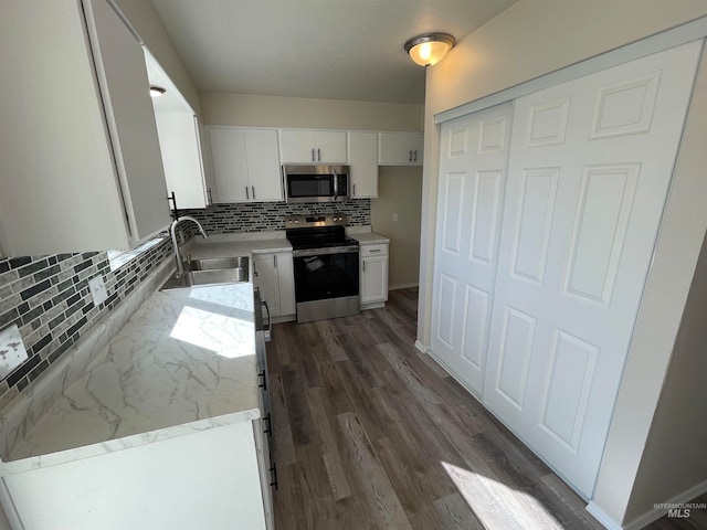 kitchen with appliances with stainless steel finishes, white cabinetry, backsplash, dark hardwood / wood-style floors, and sink