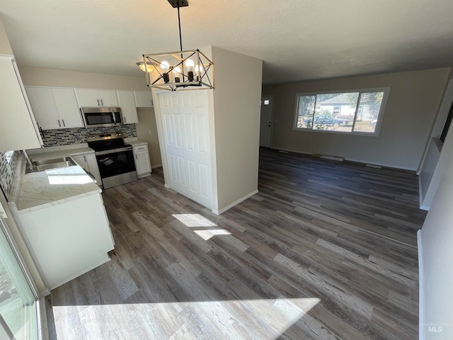 kitchen featuring white cabinetry, appliances with stainless steel finishes, decorative light fixtures, and dark hardwood / wood-style flooring