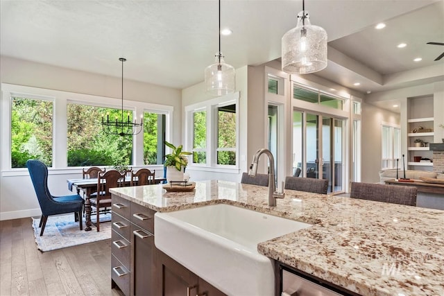 2165 N Luge Ave, Eagle, ID 83616 - kitchen featuring a sink, hardwood / wood-style flooring, dark brown cabinetry, light stone counters, and decorative light fixtures