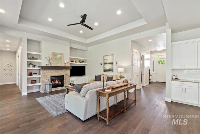 2165 N Luge Ave, Eagle, ID 83616 - living room featuring a raised ceiling, baseboards, ceiling fan, dark wood finished floors, and built in shelves