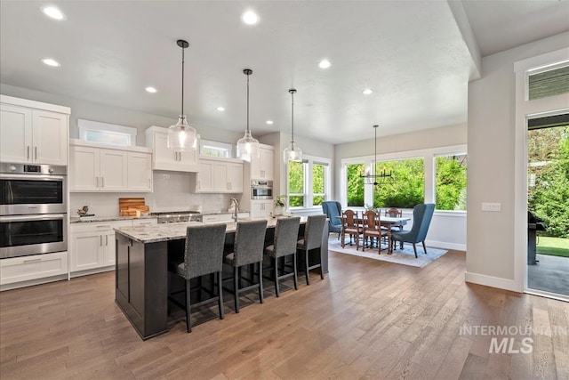 2165 N Luge Ave, Eagle, ID 83616 - kitchen featuring double oven, recessed lighting, an island with sink, white cabinetry, and wood finished floors