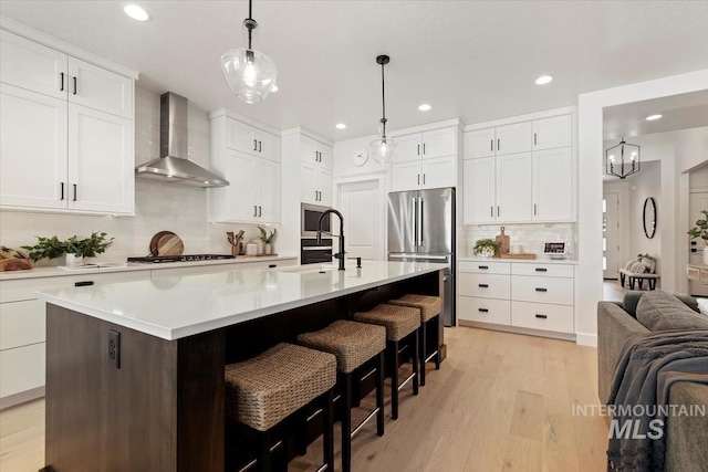 kitchen with freestanding refrigerator, recessed lighting, and wall chimney range hood