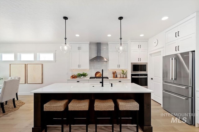 kitchen with light countertops, wall chimney range hood, white cabinets, and stainless steel appliances