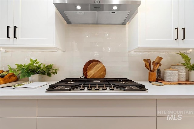 room details with white cabinetry, light countertops, stainless steel gas stovetop, and exhaust hood