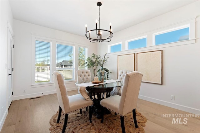 dining area featuring baseboards, an inviting chandelier, visible vents, and light wood-type flooring