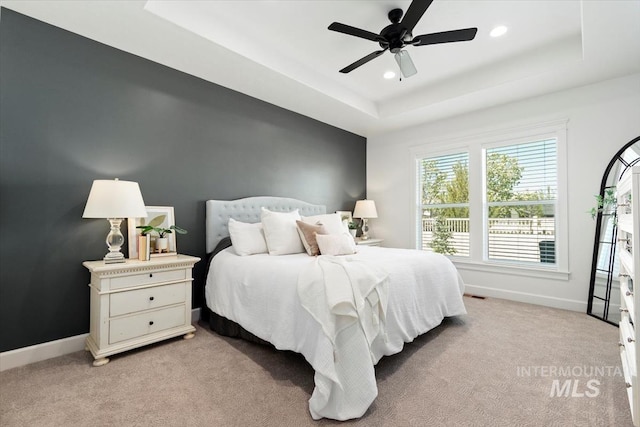 bedroom with light carpet, a tray ceiling, visible vents, baseboards, and recessed lighting