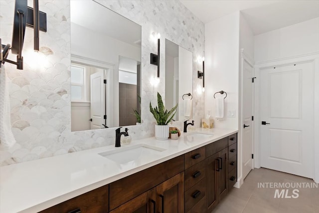 full bath featuring double vanity, tile patterned floors, and a sink