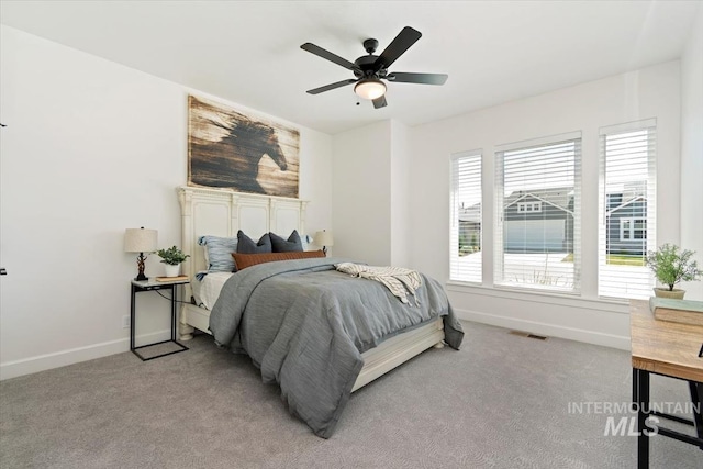 bedroom with baseboards, a ceiling fan, visible vents, and light carpet