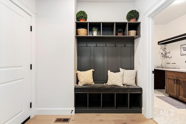 mudroom featuring light wood-type flooring, baseboards, and visible vents