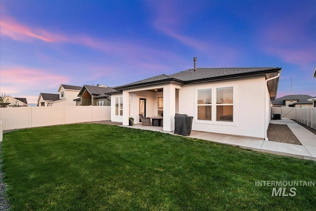 back of property with a yard, a patio, a fenced backyard, and stucco siding