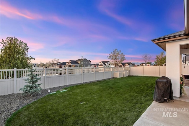 yard at dusk featuring a fenced backyard and a residential view