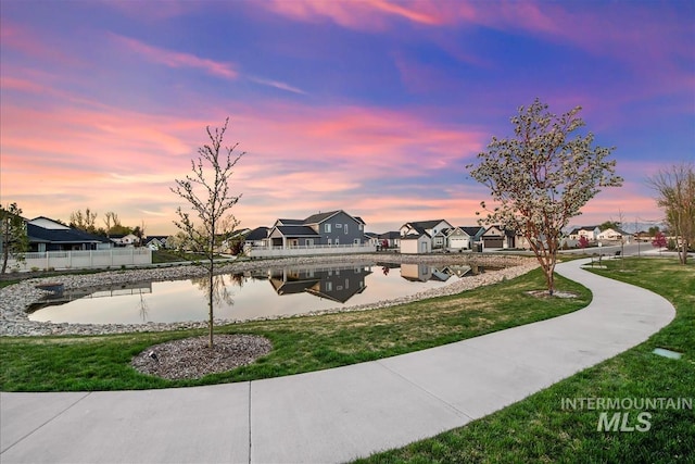 view of home's community featuring a lawn, fence, a water view, and a residential view