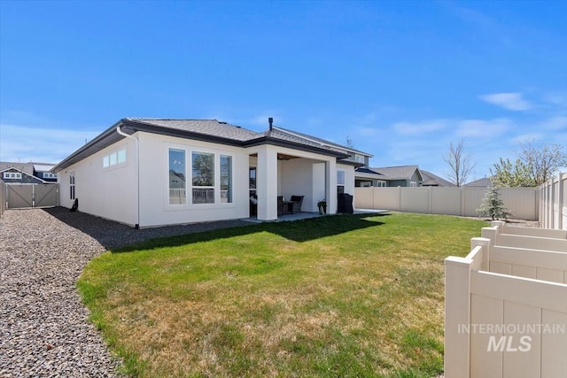 rear view of house featuring a lawn, a fenced backyard, a patio area, and stucco siding