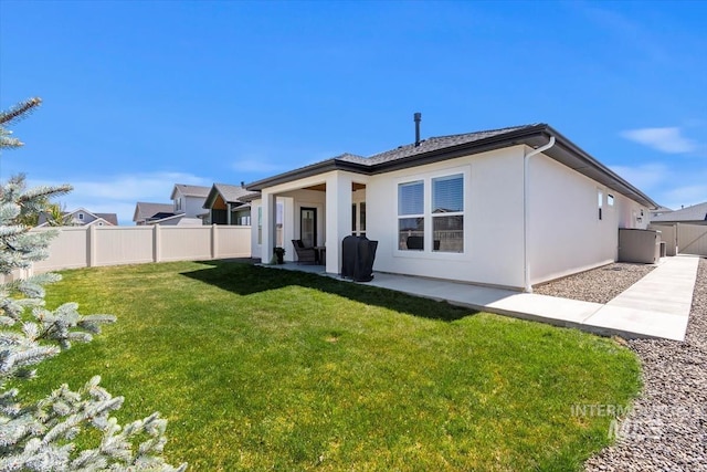 back of house featuring stucco siding, fence, and a yard