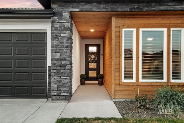 property entrance with stone siding and a garage