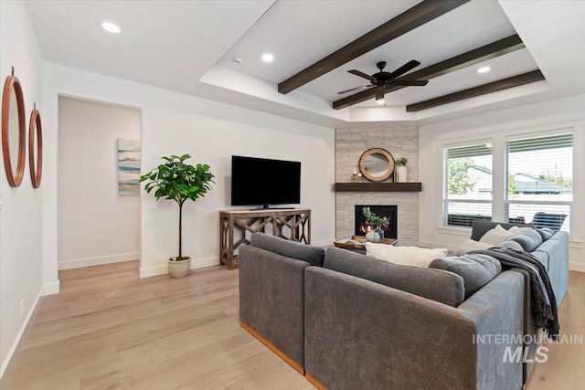 living area featuring light wood finished floors, a ceiling fan, and baseboards