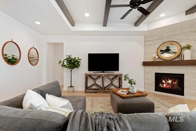 living area featuring a ceiling fan, wood finished floors, beamed ceiling, a tiled fireplace, and recessed lighting