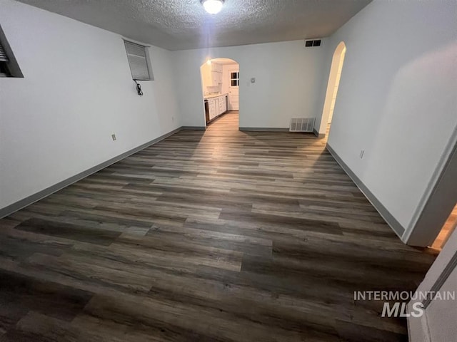 empty room with dark hardwood / wood-style floors and a textured ceiling