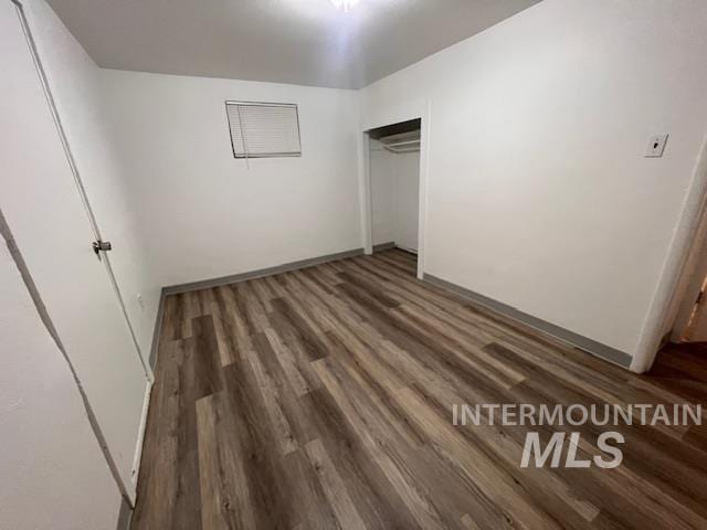 unfurnished bedroom with dark hardwood / wood-style flooring and a closet