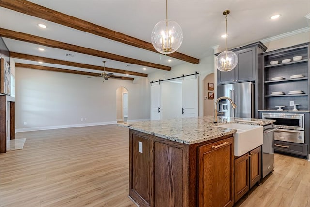 kitchen with pendant lighting, sink, a kitchen island with sink, high quality fridge, and a barn door