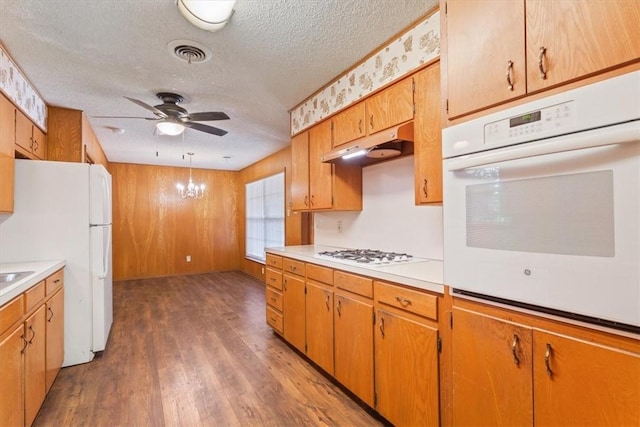 kitchen with a textured ceiling, ceiling fan with notable chandelier, white appliances, and hardwood / wood-style flooring