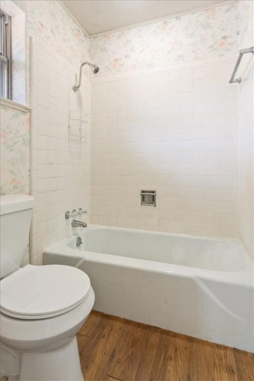 bathroom with hardwood / wood-style floors, tiled shower / bath combo, and toilet