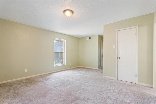 unfurnished room featuring light carpet and a textured ceiling