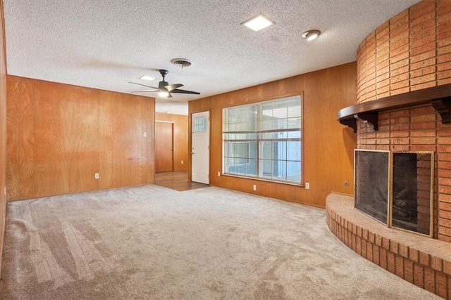 unfurnished living room with carpet flooring, wood walls, a fireplace, and ceiling fan