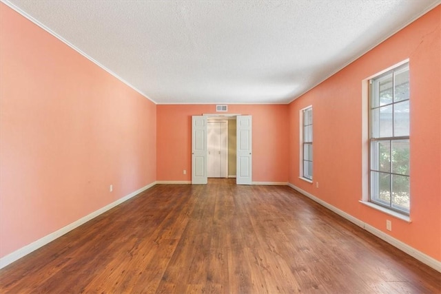 unfurnished room featuring plenty of natural light, wood-type flooring, a textured ceiling, and ornamental molding