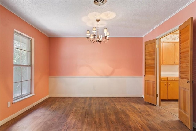 unfurnished room featuring hardwood / wood-style floors, a textured ceiling, an inviting chandelier, and ornamental molding