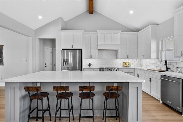 kitchen with light stone countertops, a center island, white cabinets, and appliances with stainless steel finishes